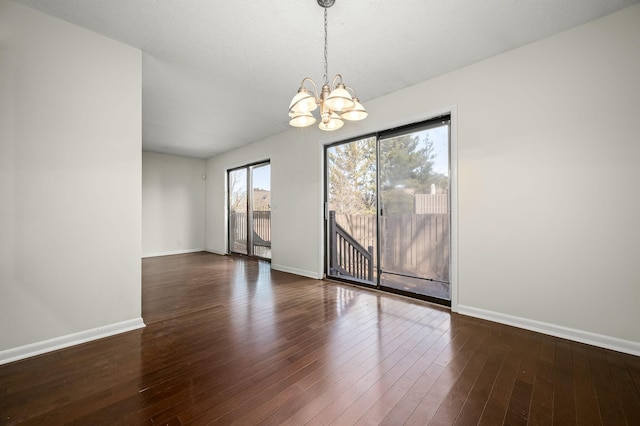 unfurnished room with dark hardwood / wood-style floors and a notable chandelier