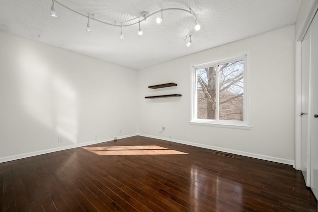 empty room with dark hardwood / wood-style floors and a textured ceiling