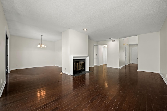 unfurnished living room with an inviting chandelier, dark hardwood / wood-style flooring, and a textured ceiling