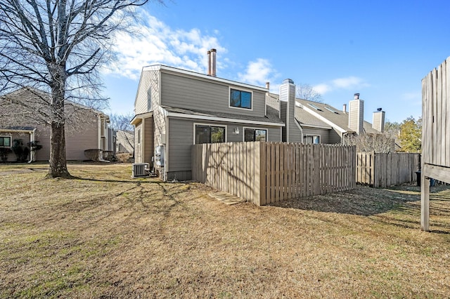 rear view of house featuring cooling unit and a lawn