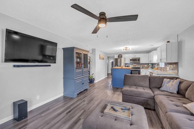 living room with ceiling fan, sink, and hardwood / wood-style flooring