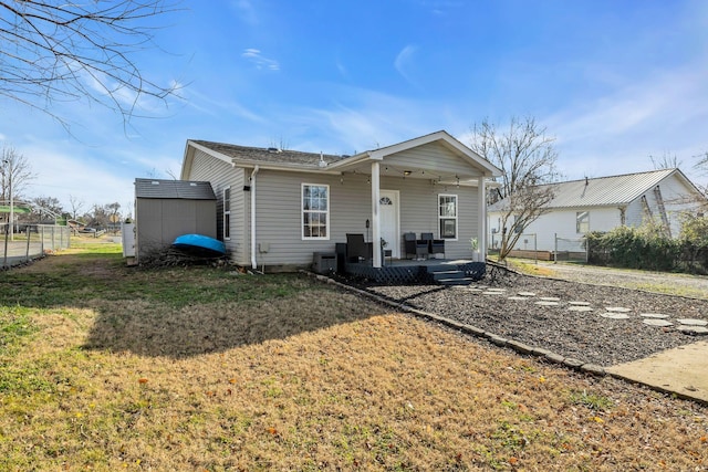 rear view of house with a lawn and a storage unit