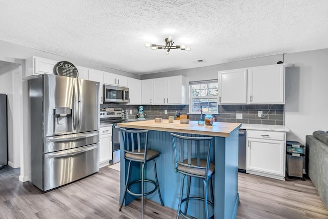 kitchen featuring white cabinetry, a breakfast bar, stainless steel appliances, and wood counters