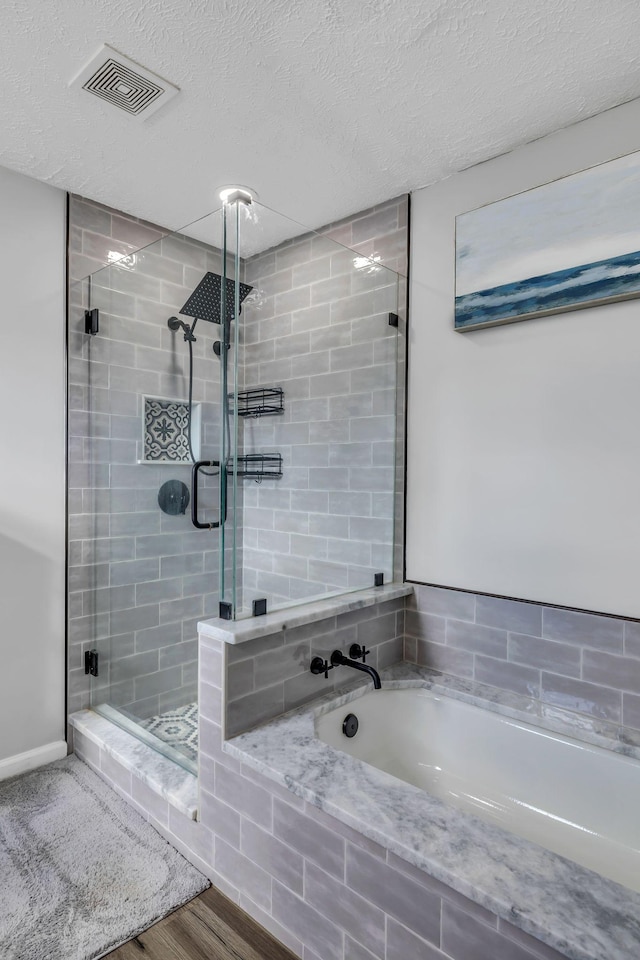 bathroom featuring plus walk in shower, wood-type flooring, and a textured ceiling