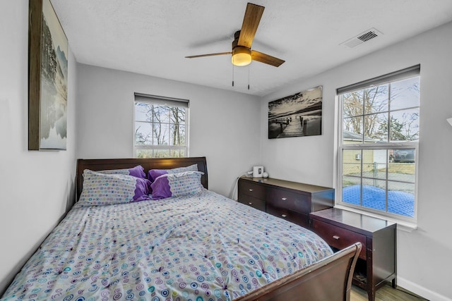 bedroom with hardwood / wood-style flooring, ceiling fan, and a textured ceiling