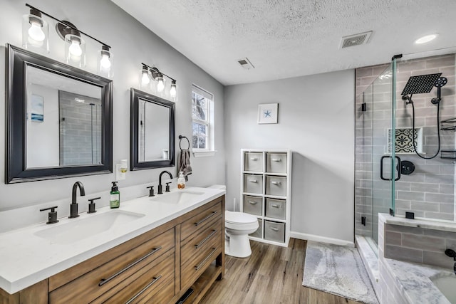 bathroom featuring hardwood / wood-style floors, a textured ceiling, toilet, a shower with door, and vanity