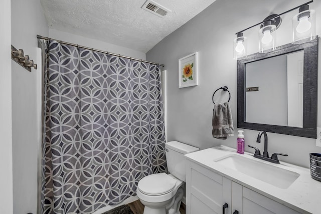 bathroom with vanity, a textured ceiling, and toilet