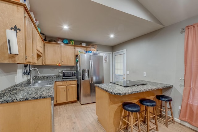 kitchen with sink, light wood-type flooring, appliances with stainless steel finishes, a kitchen bar, and kitchen peninsula