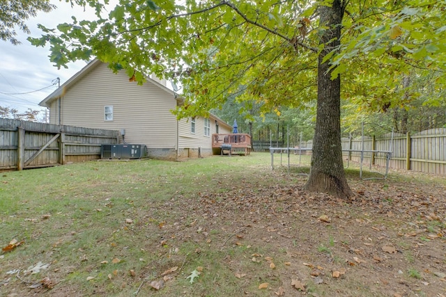 view of yard featuring a trampoline, central AC unit, and a deck