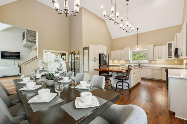 dining area with sink, high vaulted ceiling, dark hardwood / wood-style floors, and an inviting chandelier