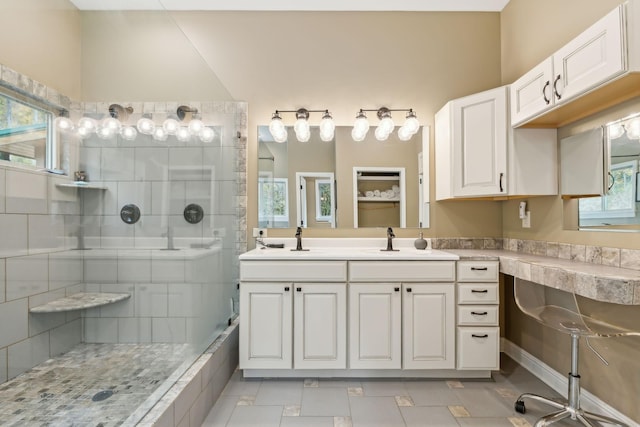 bathroom with tile patterned flooring, vanity, and tiled shower