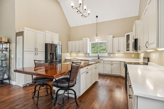 kitchen with white cabinets, sink, a kitchen island, stainless steel appliances, and a chandelier