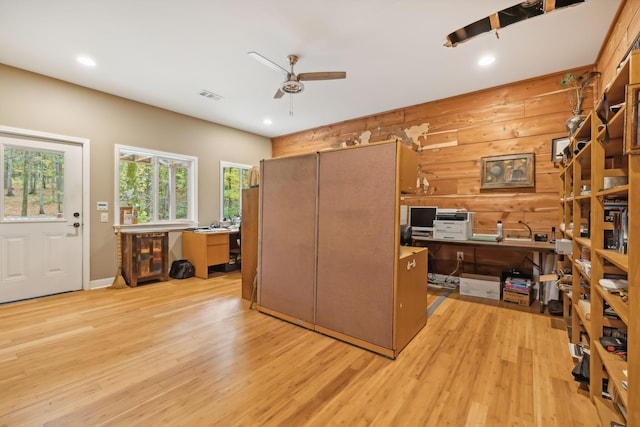 office featuring ceiling fan, light hardwood / wood-style floors, and wood walls