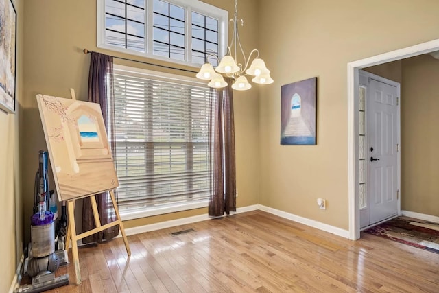 unfurnished dining area featuring hardwood / wood-style flooring and an inviting chandelier