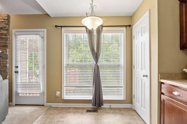 doorway to outside featuring light colored carpet and a wealth of natural light