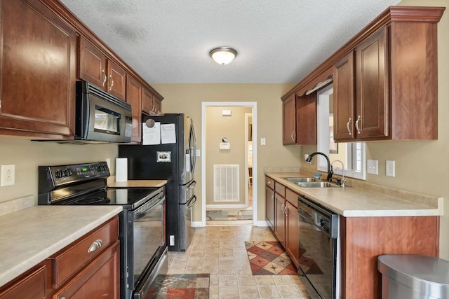 kitchen with sink, black appliances, and a textured ceiling