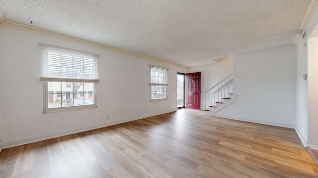 interior space featuring light wood-type flooring, a textured ceiling, and ornamental molding