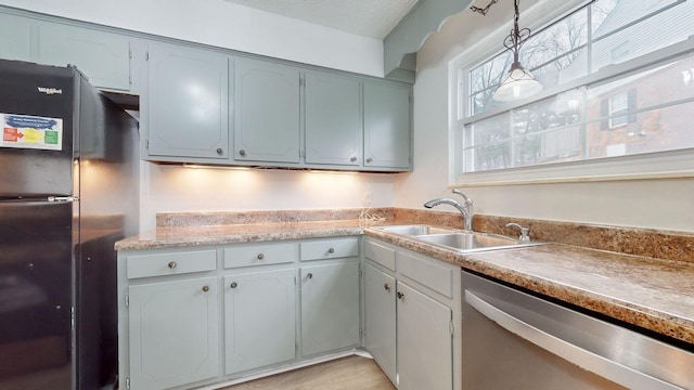 kitchen with pendant lighting, black fridge, sink, stainless steel dishwasher, and gray cabinets