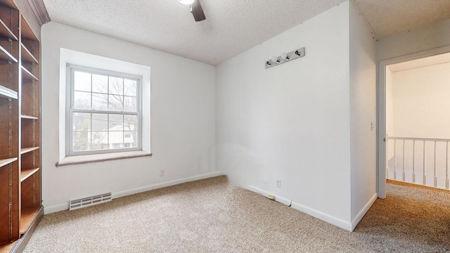 empty room featuring carpet flooring, ceiling fan, and a textured ceiling