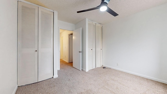 unfurnished bedroom with ceiling fan, light colored carpet, and a textured ceiling