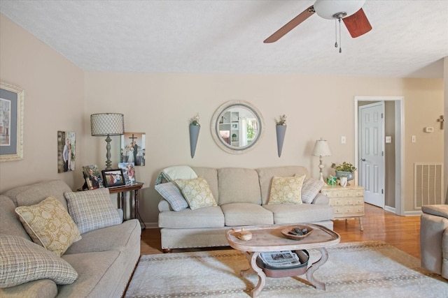 living room featuring hardwood / wood-style floors, ceiling fan, and a textured ceiling