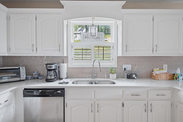 kitchen featuring stainless steel dishwasher, backsplash, white cabinetry, and sink