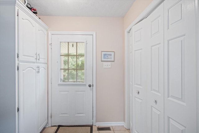 doorway featuring light tile patterned flooring and a textured ceiling