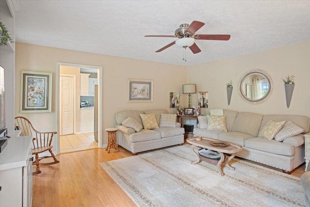 living room featuring ceiling fan, light hardwood / wood-style floors, and a textured ceiling