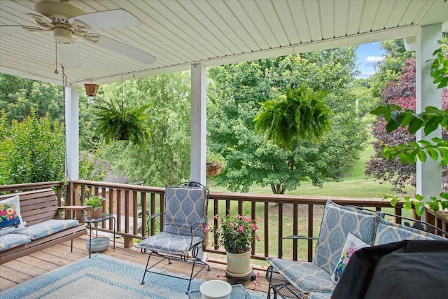 wooden terrace featuring ceiling fan and a lawn