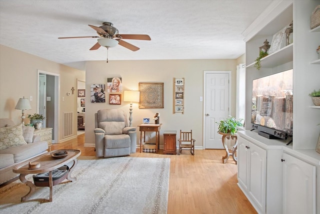 living room with a textured ceiling, light hardwood / wood-style flooring, and ceiling fan