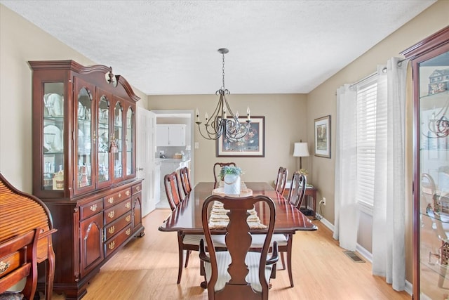 dining room featuring a chandelier, a textured ceiling, and light hardwood / wood-style flooring