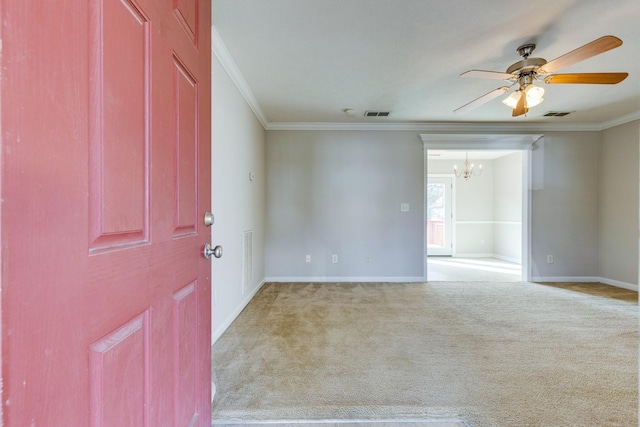 carpeted spare room with ceiling fan with notable chandelier and crown molding