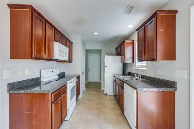 kitchen featuring white appliances, sink, and dark stone counters