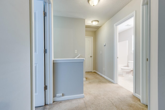 hall with a textured ceiling and light carpet