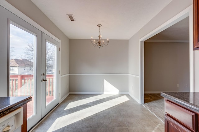 unfurnished dining area with french doors and an inviting chandelier