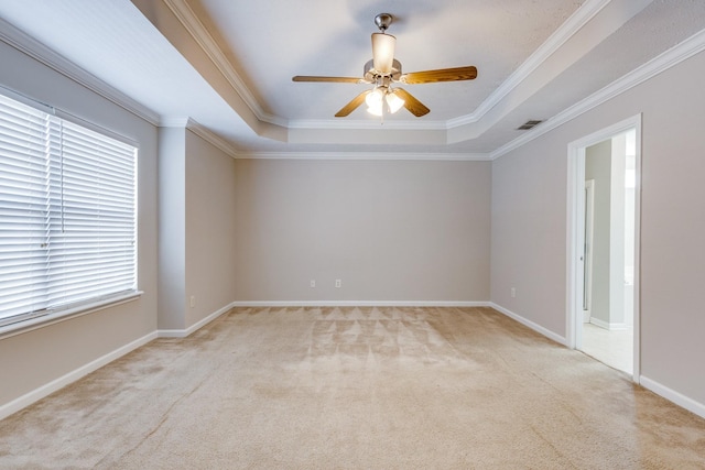 carpeted empty room featuring a raised ceiling, ceiling fan, and crown molding