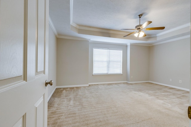 carpeted empty room with a tray ceiling, crown molding, and ceiling fan