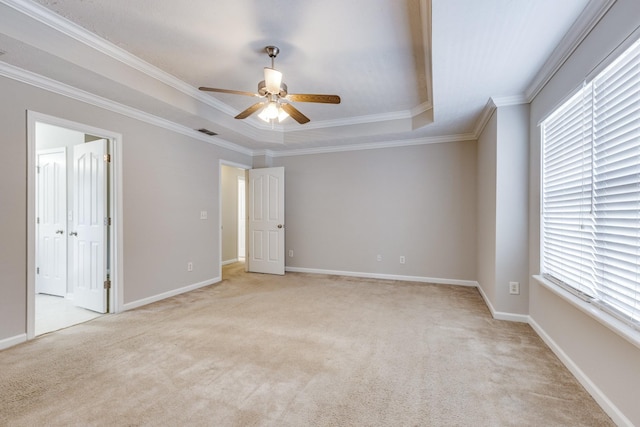 carpeted spare room with a tray ceiling, ceiling fan, and crown molding