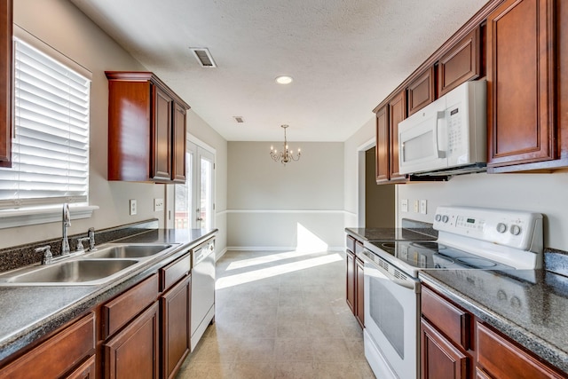 kitchen with a textured ceiling, white appliances, sink, decorative light fixtures, and a chandelier