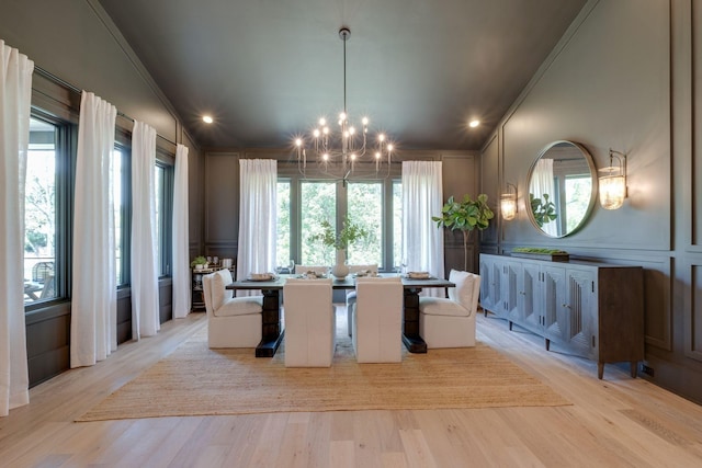 dining area with crown molding, light hardwood / wood-style floors, and a notable chandelier