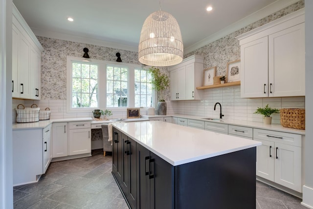 kitchen with sink, pendant lighting, an inviting chandelier, white cabinets, and a center island