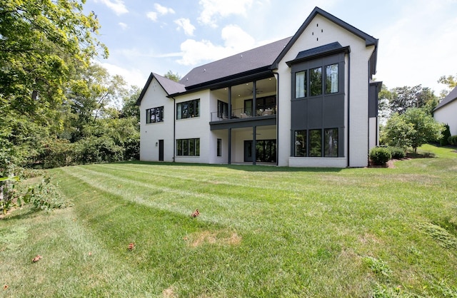 back of property with a lawn, ceiling fan, and a balcony