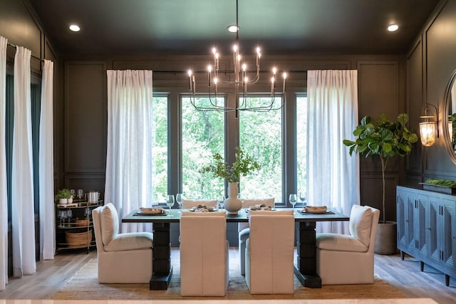 dining room with light wood-type flooring, a healthy amount of sunlight, and a notable chandelier