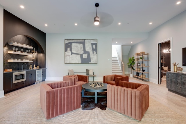 living room with wine cooler, light hardwood / wood-style flooring, wet bar, and ceiling fan