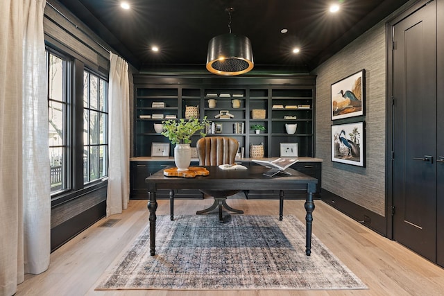 office featuring built in shelves, plenty of natural light, and light hardwood / wood-style flooring