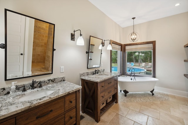 bathroom featuring a chandelier, vanity, and a bathtub