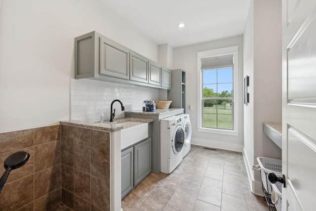 laundry area with cabinets, light tile patterned floors, separate washer and dryer, and sink