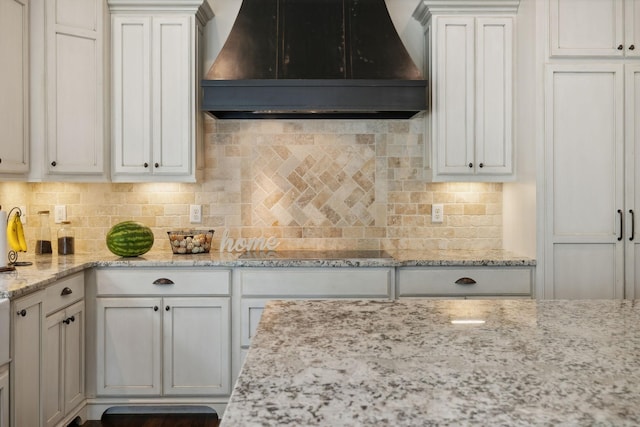 kitchen with backsplash, black electric cooktop, white cabinets, and custom exhaust hood