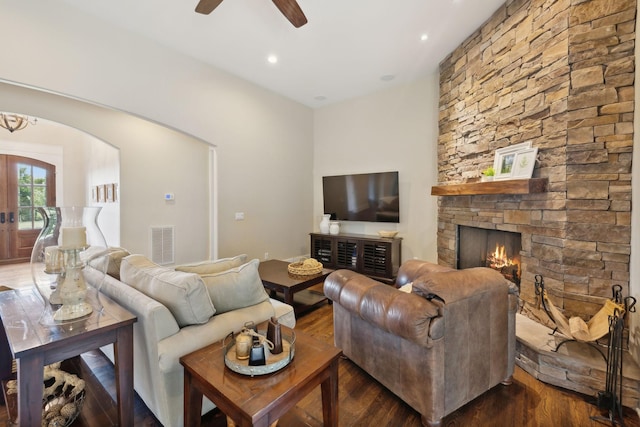 living room featuring ceiling fan, dark hardwood / wood-style flooring, a stone fireplace, and french doors