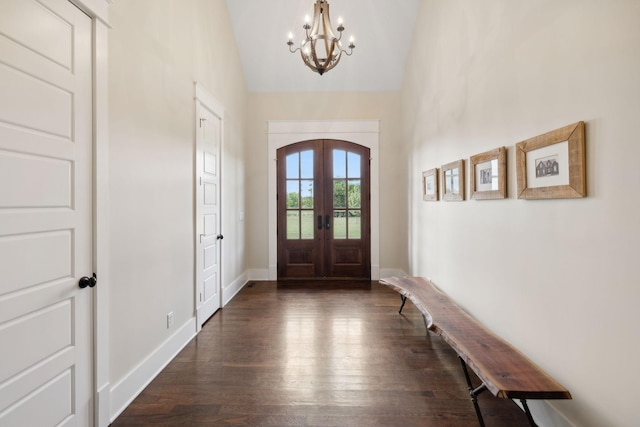 foyer entrance featuring a chandelier, vaulted ceiling, dark wood-type flooring, and french doors